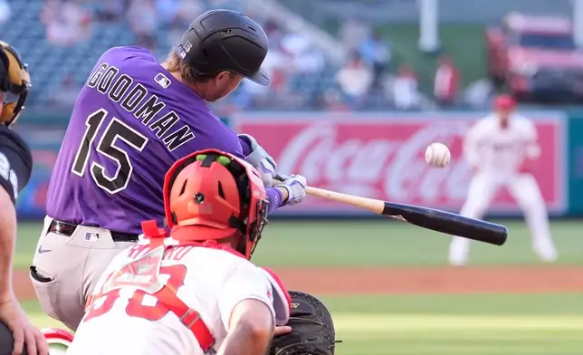 Colorado Rockies' Hunter Goodman, left, hits a solo home run as Los Angeles Angels catcher Sebastián Rivero watches during the second inning of a baseball game Tuesday, June 2, 2026, in Anaheim, Calif. (AP Photo/Mark J. Terrill)