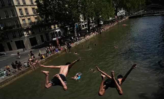 FILE - Parisians bath in the Canal Saint-Martin in Paris, as the national weather service, Meteo France, placed 54 departments, about half the country, under a red heat wave alert, on June 23, 2026. (AP Photo/Christophe Ena, File)