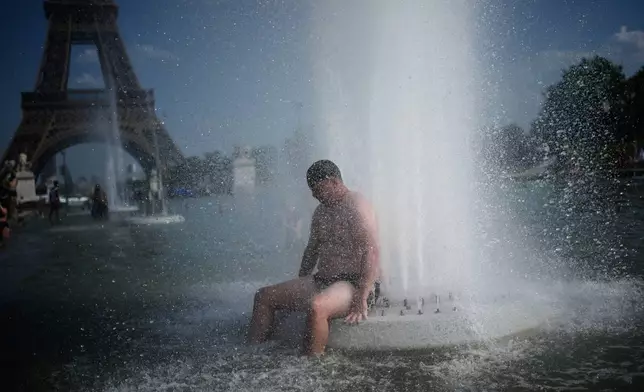 FILE - A person cools off at Trocadero fountain near the Eiffel Tower during a heat wave in Paris, on June 24, 2026. (AP Photo/Christophe Ena, File)