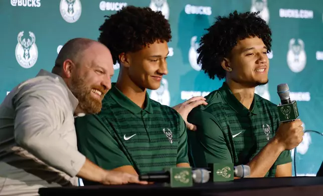 Milwaukee Bucks Head coach Taylor Jenkins, left, grabs the shoulder of Bucks first round NBA pick Brayden Burries, right as Nate Ament looks on at a Boys and Girls club in Milwaukee Thursday, June 25, 2026. (AP Photo/Jeffrey Phelps)