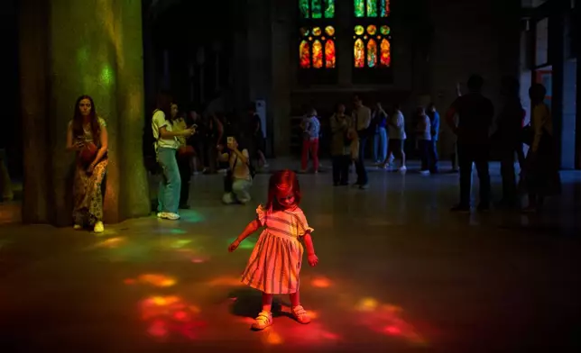 A girl plays inside Antoni Gaudí's Sagrada Família basilica illuminated in colored light from its stained-glass windows in Barcelona, Spain, Tuesday, May 26, 2026, ahead of Pope Leo XIV's visit to the city in June. (AP Photo/Emilio Morenatti)