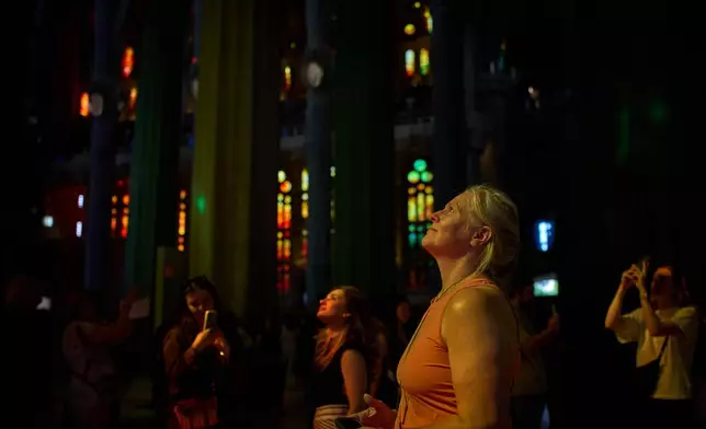 A visitor looks up inside Antoni Gaudí's Basilica of the Sagrada Familia illuminates by colored light from its stained-glass windows in Barcelona, Spain, Tuesday, May 26, 2026, ahead of Pope Leo XIV's visit to the city in June. (AP Photo/Emilio Morenatti)