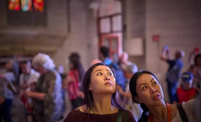 Visitors gaze upward inside the Basilica of the Sagrada Familia in Barcelona, Spain, Tuesday, May 26, 2026, as Antoni Gaudí's unfinished masterpiece prepares for Pope Leo XIV's visit to the city in June. (AP Photo/Emilio Morenatti)