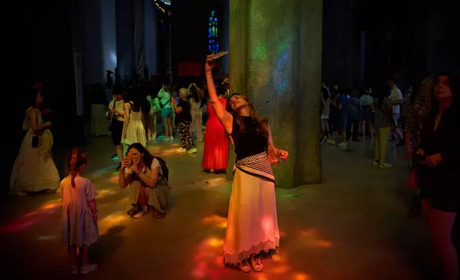 Visitors take photos inside Antoni Gaudí's Basilica of the Sagrada Familia as colored light from its stained-glass windows illuminates the interior in Barcelona, Spain, Tuesday, May 26, 2026, ahead of Pope Leo XIV's visit to the city in June. (AP Photo/Emilio Morenatti)