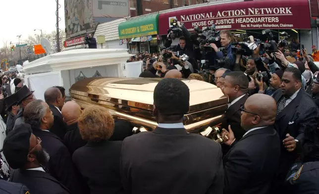 FILE - The casket of singer James Brown is placed in a horse drawn carriage before it is carried through the streets of Harlem in New York, Thursday, Dec. 28, 2006. Among those observing is Al Sharpton, lower left. (W.A. Bridges Jr./Atlanta Journal-Constitution via AP, File)