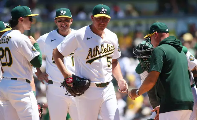 Athletics pitcher Jacob Lopez, centet, hands the ball to manger Mark Kotsay, right, after being pulled during the third inning of a baseball game against the New York Yankees, Sunday, May 31, 2026, in West Sacramento, Calif. (AP Photo/Scott Marshall)