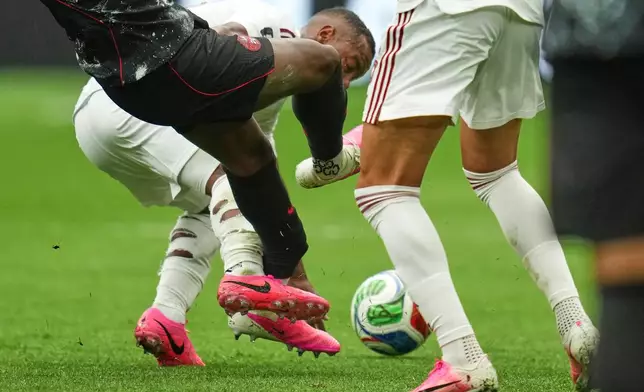Canada's Ismael Kone, left, falls while being fouled against by Qatar's Assim Madibo during the World Cup Group B soccer match in Vancouver, British Columbia, Thursday, June 18, 2026. (AP Photo/Abbie Parr)