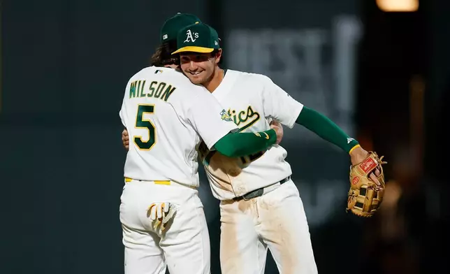 Athletics shortstop Jacob Wilson (5) and Colorado Rockies second baseman Alika Williams (12) embrace following the Athletics victory of the Colorado Rockies during a baseball game Saturday, June 13, 2026, in Las Vegas. (AP Photo/Caroline Brehman)