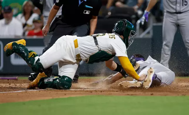 Athletics catcher Shea Langeliers, front eft, tags out Colorado Rockies' Willi Castro, bottom right, at home plate during the fifth inning of a baseball game Saturday, June 13, 2026, in Las Vegas. (AP Photo/Caroline Brehman)