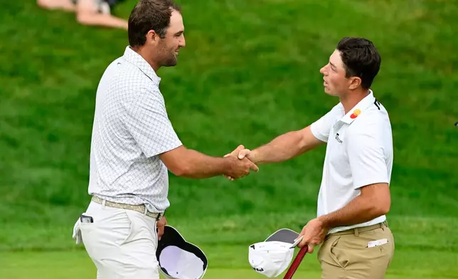 Scottie Scheffler, left, shakes hands with Viktor Hovland, right, of Norway, on the 18th green after finishing the third round of the Travelers Championship golf tournament at TPC River Highlands, Saturday, June 27, 2026, in Cromwell, Conn. (AP Photo/Jessica Hill)