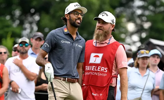 Akshay Bhatia smiles as his caddie Joe Greiner talks to him at the first hole during the third round of the Travelers Championship golf tournament at TPC River Highlands, Saturday, June 27, 2026, in Cromwell, Conn. (AP Photo/Jessica Hill)