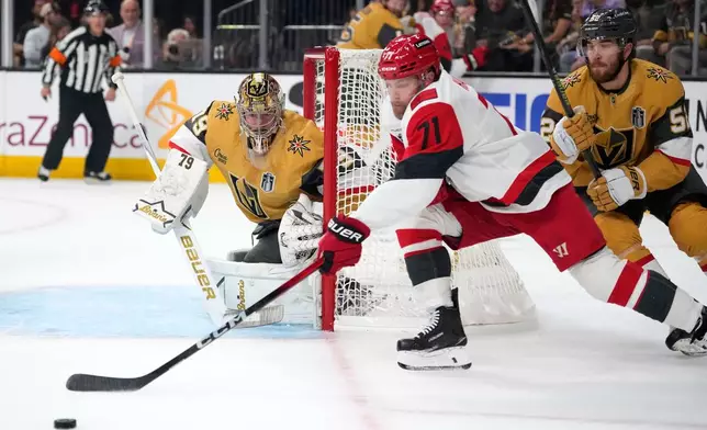 Carolina Hurricanes left wing Taylor Hall, center, attempts a wrap around as Vegas Golden Knights goaltender Carter Hart, left, and defenseman Dylan Coghlan defend during the first period in Game 3 of the NHL hockey Stanley Cup Final series Saturday, June 6, 2026, in Las Vegas. (AP Photo/John Locher)
