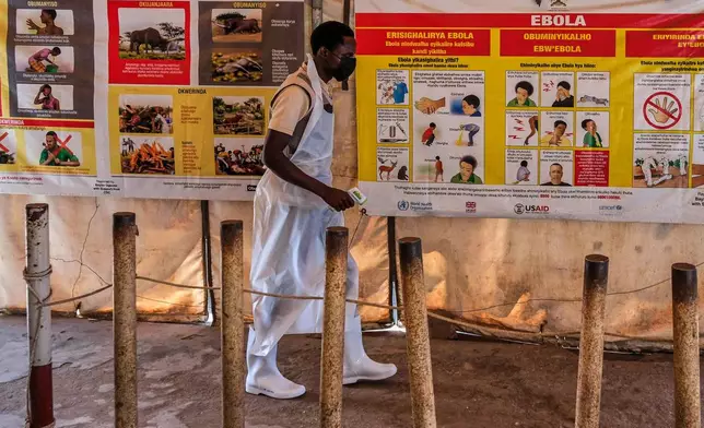 A health worker walks past Ebola warning and instruction posters at a temporary health clinic at the Mpondwe border crossing linking Uganda and the Democratic Republic of the Congo, Thursday, June 4, 2026. (AP Photo/Hajarah Nalwadda)
