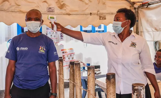 A health worker checks an individual's temperature at a temporary health clinic at the Mpondwe border crossing linking Uganda and the Democratic Republic of the Congo, Thursday, June 4, 2026. (AP Photo/Hajarah Nalwadda)