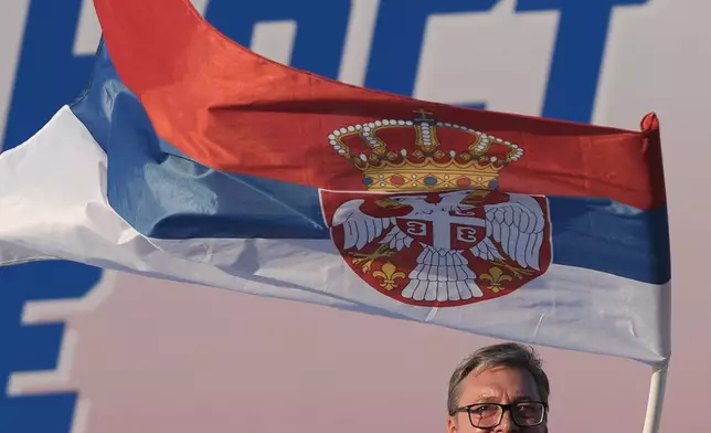Serbian President Aleksandar Vucic waves a Serbian flag during a rally of the ruling Serbian Progressive Party (SNS) in Belgrade, Serbia, Saturday, June 27, 2026, where he announced that he will resign in the coming weeks. (AP Photo/Darko Vojinovic)