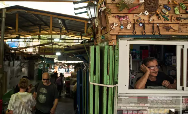 A vendor looks on from the window of his shop at a local street market following air raid sirens warning of incoming Iranian missiles in Haifa, northern Israel, Monday, June 8, 2026. (AP Photo/Leo Correa)