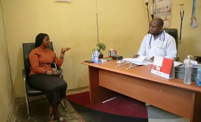 Dr. Babah Mutuza Lusungu, right, a doctor at "Dieu Est Grand" Medical Center, attends to a woman in his office in Beni, Congo, Monday, June 1, 2026. (AP Photo/Kitsa Musayi Sebastien)