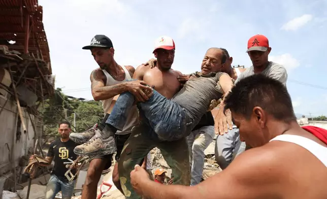 Neighbors carry a man rescued from the rubble of a collapsed building the day after earthquakes struck La Guaira, Venezuela, Thursday, June 25, 2026. (AP Photo/Pedro Mattey)