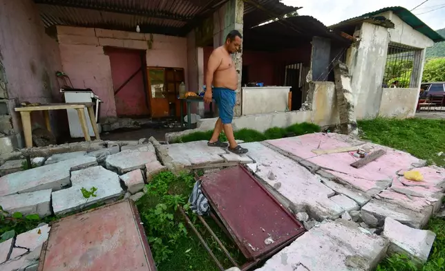 A man walks over the fallen walls of his home in Moron, near the epicenter of two earthquakes that struck Venezuela the day before, Thursday, June 25, 2026. (AP Photo/Jacinto Oliveros)