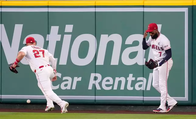 Los Angeles Angels right fielder Jo Adell touches his head after he misplayed a ball hit by Colorado Rockies' TJ Rumfield that hit him in the head and then bounced out for a solo home run as center fielder Mike Trout goes after the ball during the fourth inning of a baseball game Tuesday, June 2, 2026, in Anaheim, Calif. (AP Photo/Mark J. Terrill)