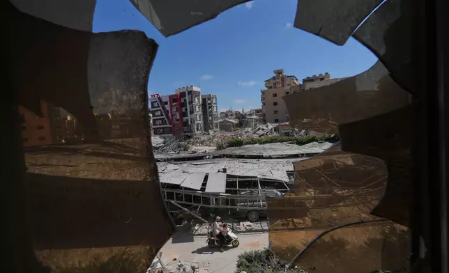 Buildings damaged by Israeli strikes are seen through shattered glass from the Jabal Amel Hospital in the southern port city of Tyre, Lebanon, Thursday, June 18, 2026. (AP Photo/Hassan Ammar)