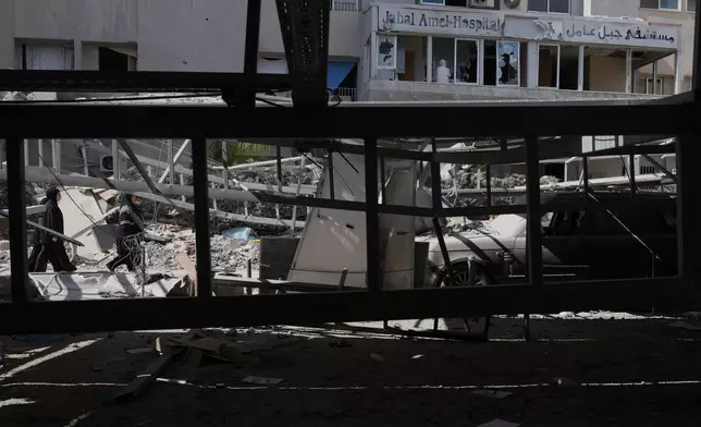 Women walk past debris outside Jabal Amel Hospital, which was heavily damaged in Israeli strikes that hit nearby buildings earlier this month, in the southern port city of Tyre, Lebanon, Thursday, June 18, 2026. (AP Photo/Hassan Ammar)