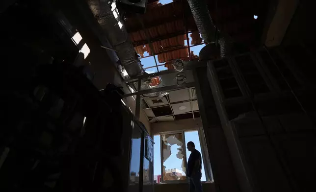 A hospital staff member looks out from a window at Jabal Amel Hospital, which was heavily damaged in Israeli strikes that hit nearby buildings earlier this month, in the southern port city of Tyre, Lebanon, Thursday, June 18, 2026. (AP Photo/Hassan Ammar)