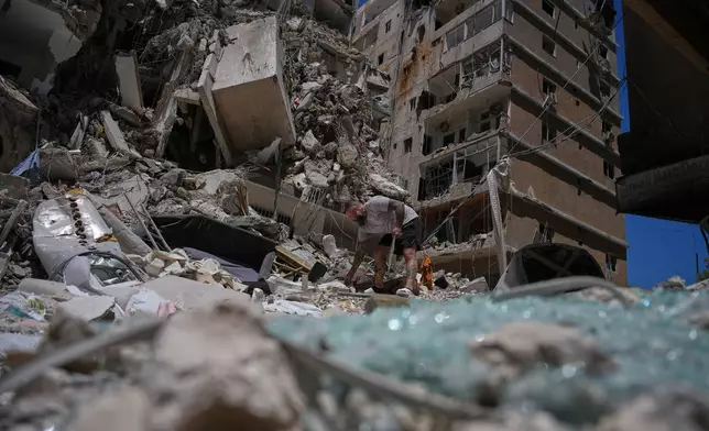 Barber Wissam Srour, 41, searches for belongings in the rubble of his barbershop, damaged in an Israeli strike, in the southern port city of Tyre, Lebanon, Friday, June 19, 2026. (AP Photo/Hassan Ammar)