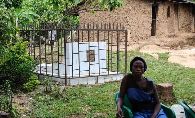 A woman sits beside a caged grave of a person who died from the first outbreak of Bundibugyo virus, a particular strain of Ebola, in Kikyo Trading village, Bundibugyo District, Uganda, Wednesday, June 3, 2026. (AP Photo/Hajarah Nalwadda)