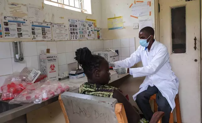 A laboratory technician works with a patient at Kikyo Health Centre IV in Kikyo Trading village, Bundibugyo District, Uganda, Wednesday, June 3, 2026. (AP Photo/Hajarah Nalwadda)