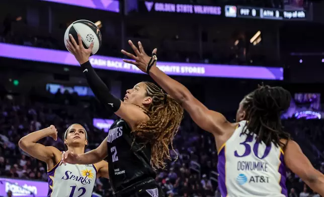 Golden State Valkyries' Veronice Burton, center, goes up to shoot between Los Angeles Sparks' Nneka Ogwumike (30) and Rae Burrell (12) in the first half of a WNBA basketball game Monday, June 15, 2026, in San Francisco. (Carlos Avila Gonzalez/San Francisco Chronicle via AP)