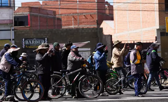 Residentes take pictures at police clearing a highway blocked by protesters after President Rodrigo Paz declared a state of emergency in El Alto, Bolivia, Saturday, June 20, 2026. (AP Photo/Juan Karita)
