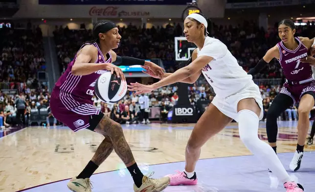 Toronto Tempo's Brittney Sykes, left, keeps the ball from Atlanta Dream's Angel Reese, second from left, during the first half of a WNBA basketball game in Toronto, Sunday, June 14, 2026. (Sammy Kogan/The Canadian Press via AP)