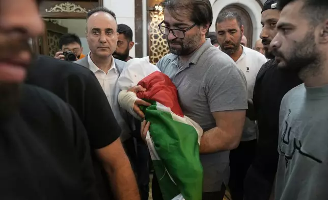 Fahd Abu Haikal, 41 carries the body of his seven month old Palestinian baby boy Sam, who was killed on Friday when, according to the Palestinian health ministry, Israeli soldiers fired at the vehicle carrying him and his parents in Tel Rumeida, during his funeral in the West Bank city of Hebron, Saturday, June 6, 2026. (AP Photo/Mahmoud Illean)