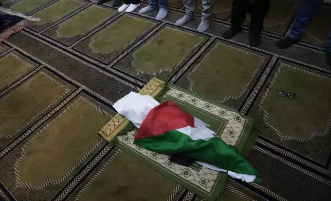 Mourners pray over the body of seven month old Palestinian baby boy Sam Fahd Abu Haikal, who was killed on Friday when, according to the Palestinian health ministry, Israeli soldiers fired at the vehicle carrying him and his parents in Tel Rumeida, during his funeral in the West Bank city of Hebron, Saturday, June 6, 2026. (AP Photo/Mahmoud Illean)