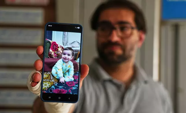 Fahd Abu Heikal, 41 displays a mobile photo of his seven month old Palestinian baby boy Sam, who was killed on Friday when Israeli soldiers fired at the vehicle carrying him and his parents, in Tel Rumeida, at a hospital in the West Bank city of Hebron Saturday, June 6, 2026. (AP Photo/Mahmoud Illean)