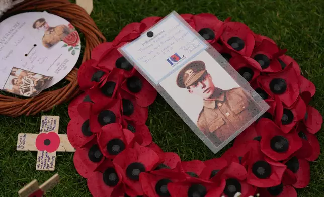 A poppy wreath and a photo next to the grave of Private Thomas Redvers Whitaker during a burial ceremony for six British soldiers of World War I, at the CWGC's Tyne Cot Cemetery in Zonnebeke, Belgium, Wednesday, June 10, 2026. (AP Photo/Virginia Mayo)