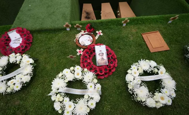 Poppy wreaths and photos stand beside the graves during a burial ceremony for six British soldiers of World War I, at the CWGC's Tyne Cot Cemetery in Zonnebeke, Belgium, Wednesday, June 10, 2026. (AP Photo/Virginia Mayo)