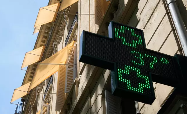 A sign outside a pharmacy displays a temperature of 37 degrees Celsius (98.6 degrees Fahrenheit) in Paris, Sunday, June 21, 2026. (AP Photo/Michel Euler)