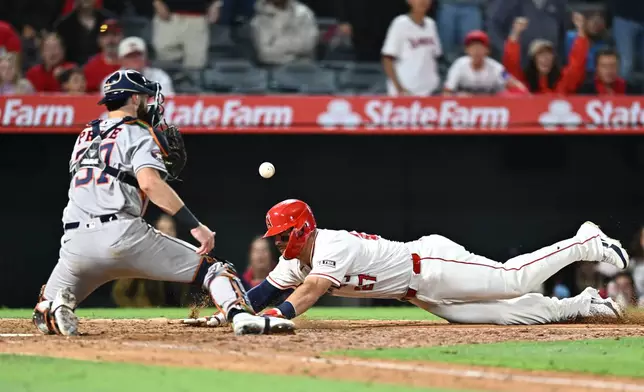 Los Angeles Angels' Mike Trout, right, slides into home base, but is called out during the 10th inning of a baseball game against the Houston Astros, Monday, June 8, 2026, in Anaheim, Calif. (AP Photo/William Liang)
