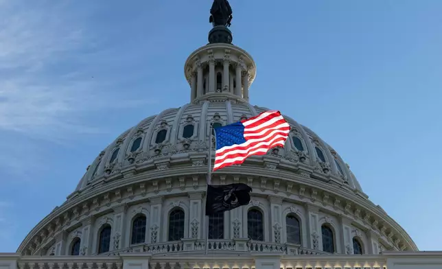 FILE - The American flag over the Capitol is illuminated by the early morning light in Washington, Oct. 1, 2025. (AP Photo/J. Scott Applewhite, File)