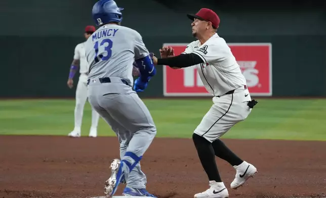 Los Angeles Dodgers' Max Muncy (13) and Arizona Diamondbacks first baseman Ildemaro Vargas, right, collide on a play in the fifth inning of a baseball game, Thursday, June 4, 2026, in Phoenix. (AP Photo/Rick Scuteri)