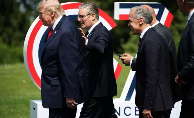 U.S. President Donald Trump, left, British Prime Minister Keir Starmer, center, and Canada's Prime Minister Mark Carney arrive for a group photo at the G7 summit in Evian-les-Bains, France, Tuesday June 16, 2026. (Isabel Infantes/Pool Photo via AP)