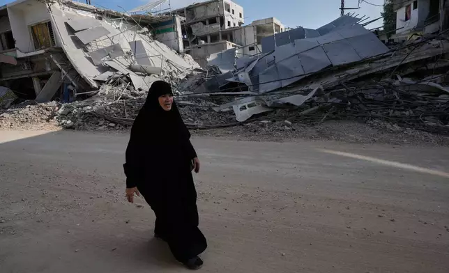 A woman returns to her village following the announcement of an initial ceasefire agreement between the United States and Iran, walks at her destroyed neighbourhood in Nabatiyeh town, southern Lebanon, Tuesday, June 16, 2026. (AP Photo/Hussein Malla)