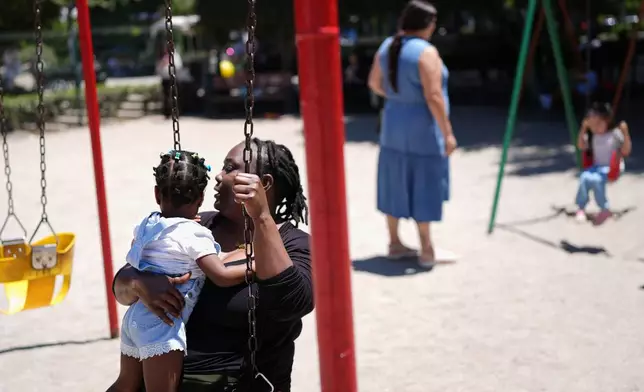 Vivianne Petit Frere holds her granddaughter Alexca as she swings with her at a playground, June 22, 2026, in Tijuana, Mexico. (AP Photo/Gregory Bull)