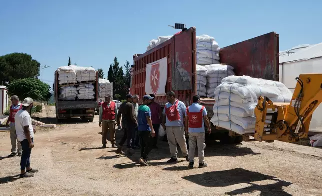 Workers unload emergency livestock feed and supplies for farmers from an aid convoy organized by the Order of Malta, a Catholic lay religious order, in the southern Christian village of Ain Ebel, Lebanon, Thursday, June 18, 2026. (AP Photo/Bilal Hussein)