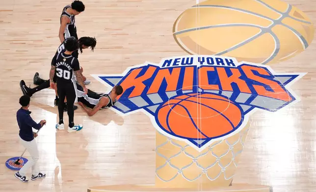 San Antonio Spurs guard Stephon Castle (5) helps up forward Victor Wembanyama (1) after being hit during the second half of Game 3 of the NBA Finals basketball series, Monday, June 8, 2026, in New York. (AP Photo/Yuki Iwamura)
