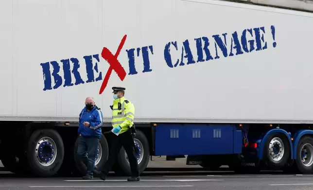 FILE - A policeman escorts the driver of a shellfish export truck as he is stopped for an unnecessary journey in London, Monday, Jan, 18, 2021. (AP Photo/Alastair Grant, File)