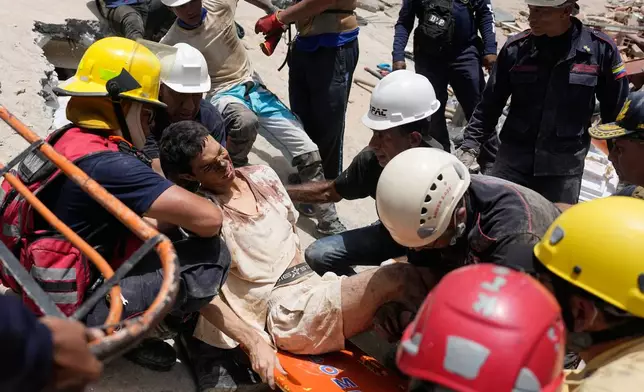 Rescue aid Daniel Cordero after pulling him from the rubble two days after an earthquake struck Catia la Mar, Venezuela, Friday, June 26, 2026. (AP Photo/Fernando Vergara)