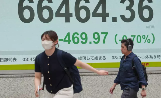 People walk in front of an electronic stock board showing Japan's Nikkei index at a securities firm Tuesday, June 2, 2026, in Tokyo. (AP Photo/Eugene Hoshiko)
